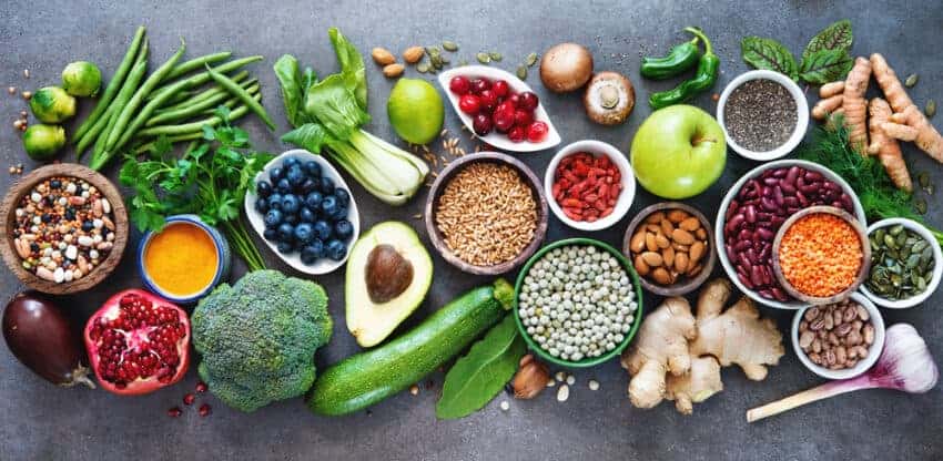 Superfoods auf einem Tisch ausgebreitet, Brokkoli, Zucchini, Ingwer, Knoblauch, Granatapfel, Blaubeeren, Pilze, Kurkuma und mehr