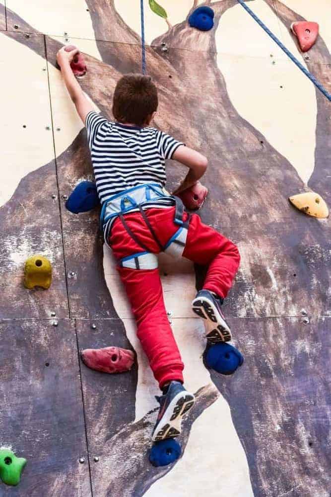Junge mit roter Hose beim Bouldern