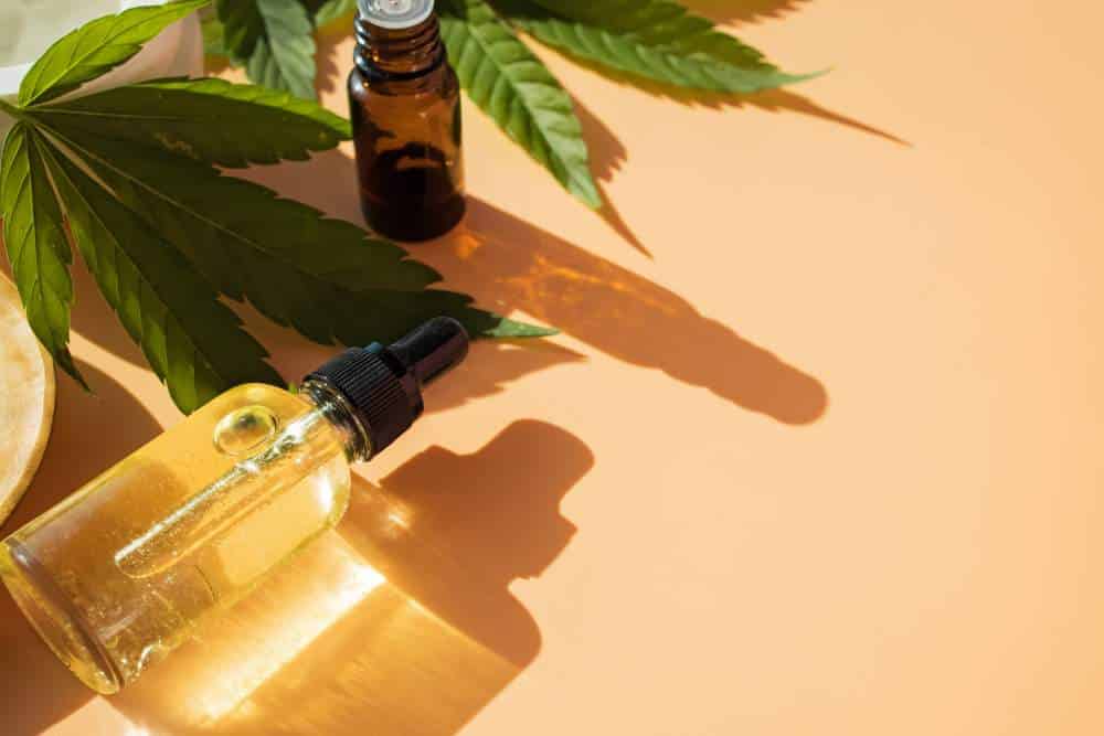 CBD Öl legal nutzen: CBD-Öl in einer kleinen Flasche neben einem Cannabisblatt