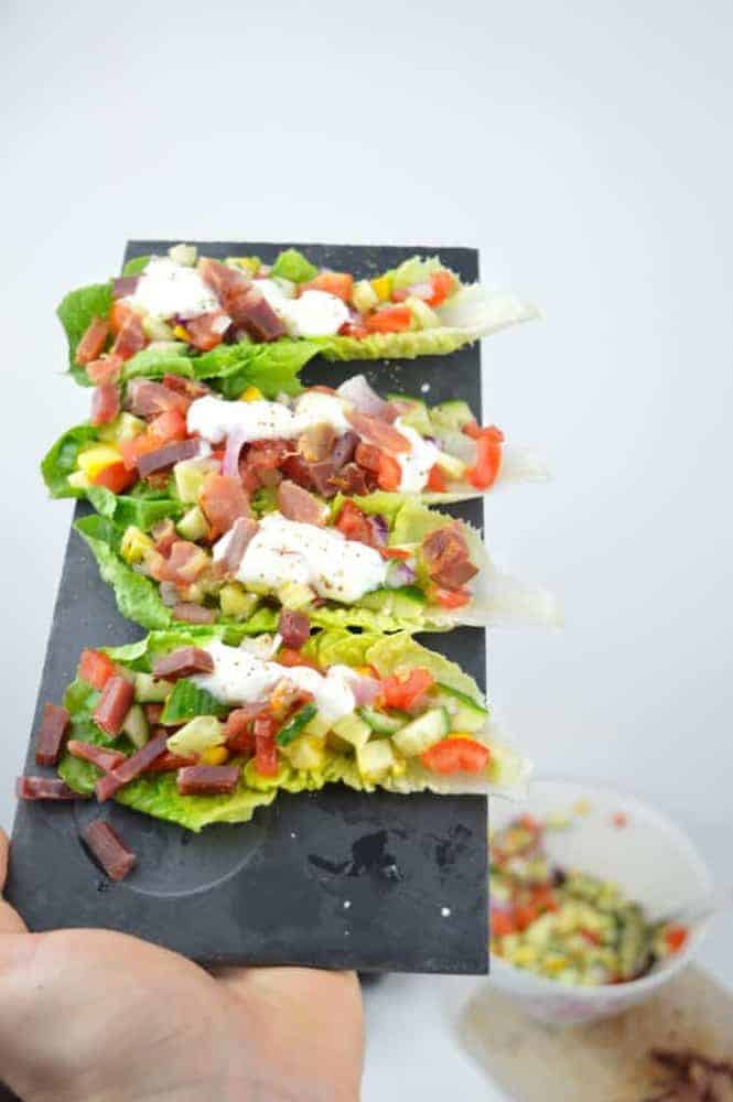 Salat Tacos von Hand auf Schieferbrett gehalten