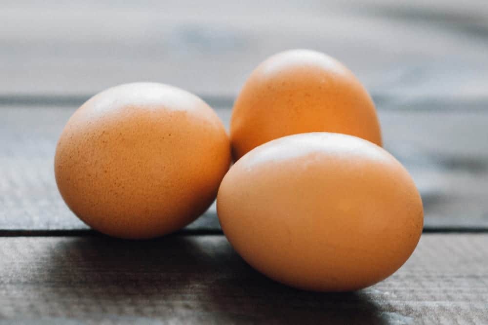 Sind Eier gesund drei Eier auf einem Holztisch