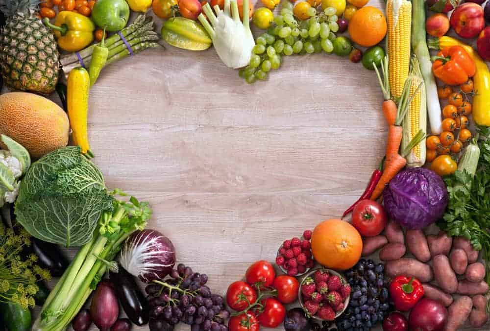 Gemüse und Obst auf Holztisch mit Herz in der Mitte