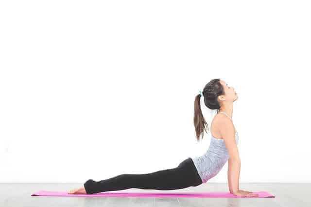 Junge Frau in Yogapose auf rosafarbener Sportmatte