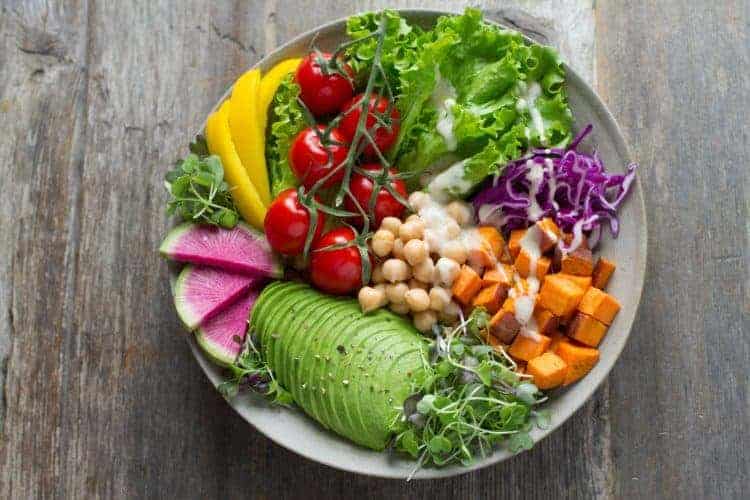 Salat mit Avocado und Kürbiswürfeln auf Holztisch