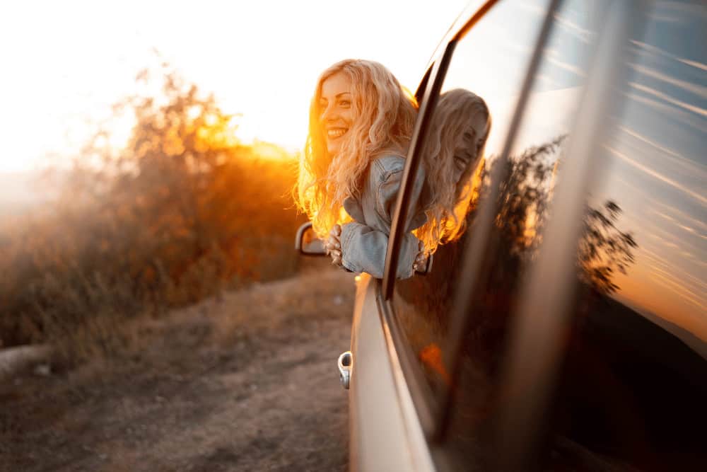 Gesund auf Reisen bleiben junge Frau schaut zum Sonnenuntergang aus dem Fenster raus
