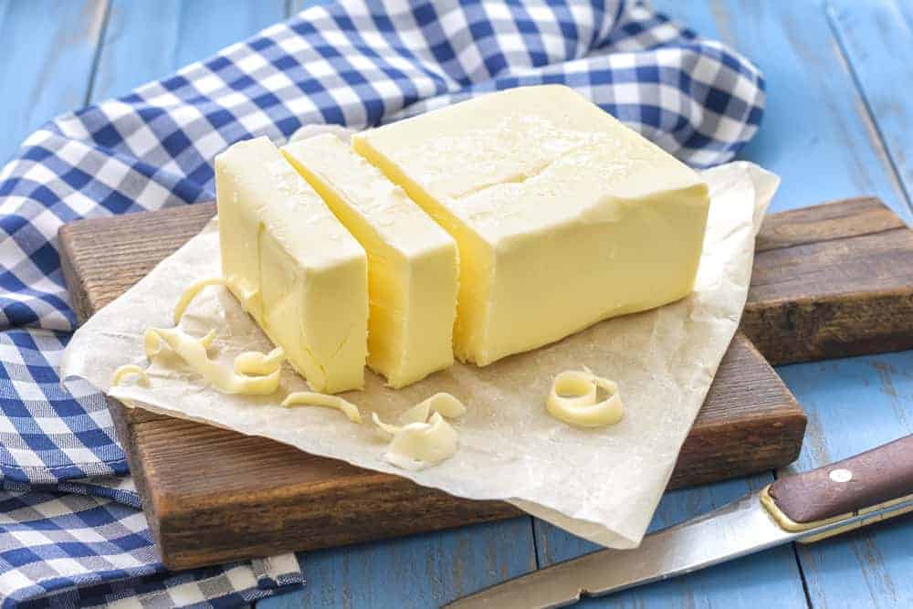 Butter als gesundes FEtt auf Holzbrett und weiß-blau karierter Tischdecke