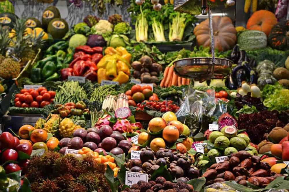 Marktstand mit Obst, Gemüse und Messingwaage