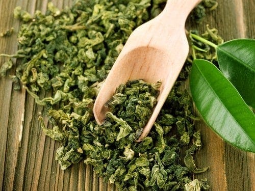 Getrockneter grüner Tee mit Holzlöffel auf Holzbrett arrangiert
