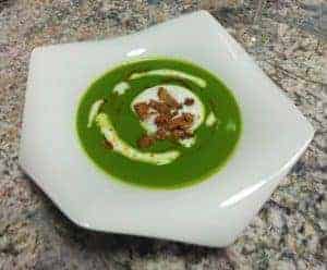 grüne Suppe in weissem Teller auf Marmor