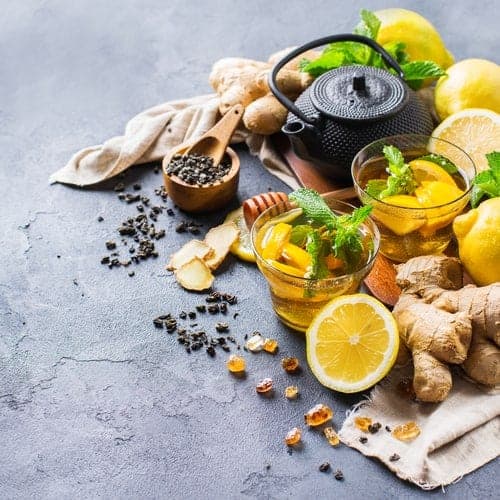 Tee, Zitrusfrüchte, Kräuter und Ingwer auf Steintisch