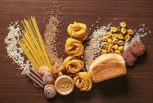 Haferflocken, neben Nudeln, Brot, Reis und Keksen auf Holztisch