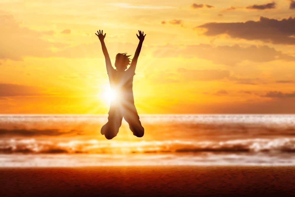 Lebensfreude steigern junge Frau spring am Strand in die Luft