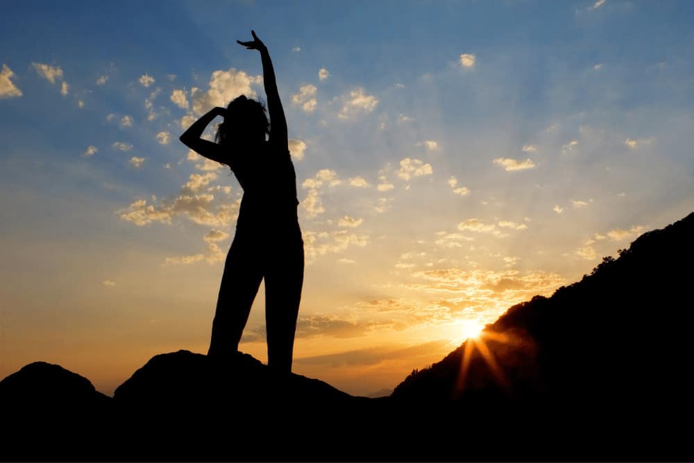Lebensfreude steigern junge Frau steht auf einem Berg in der Sonne