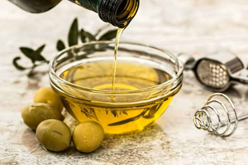 Oliven und Olivenöl in Glasschale auf weißem Hintergrund