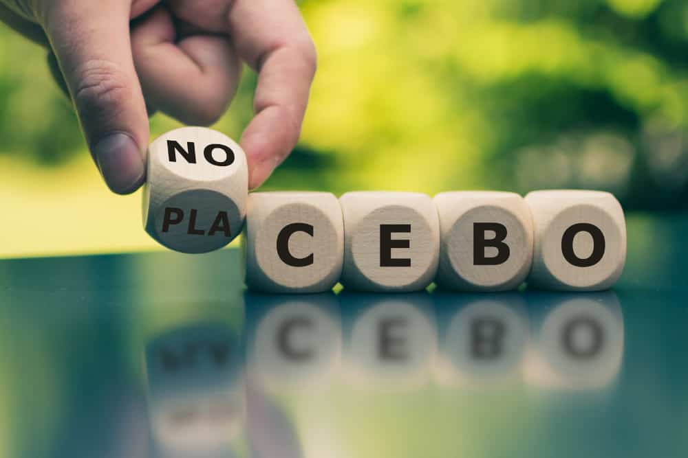 Eine Person legt das Wort Placebo aus kleinen Holzwürfeln mit Buchstaben