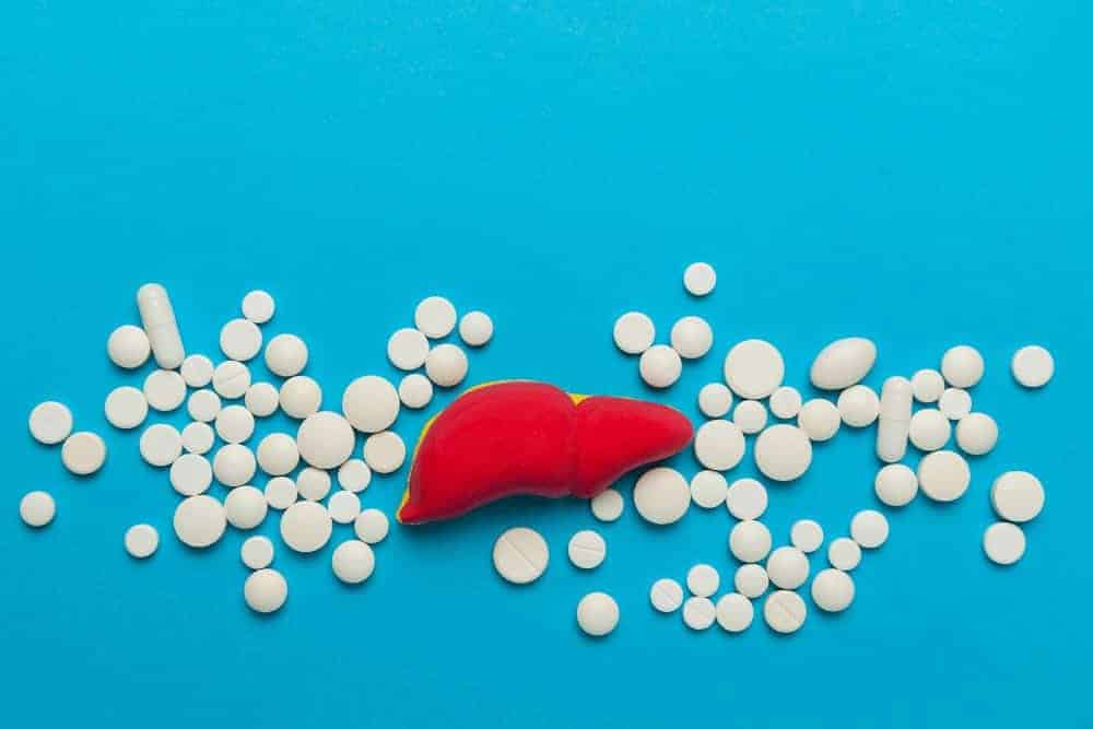 Medikamente weiße Pillen auf einem blauen Tisch und eine rote Leber