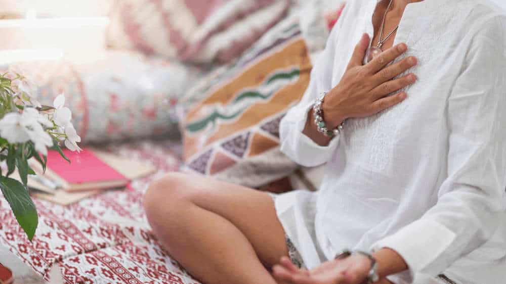 Selbstheilungskräfte stärken und aktivieren Frau beim Meditieren mit Hand auf dem Herzen