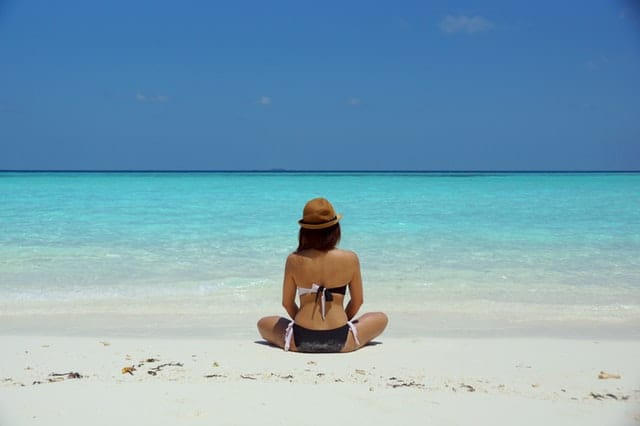 Junge Frau in Bikini am Strand vor türkisfarbenem Meer