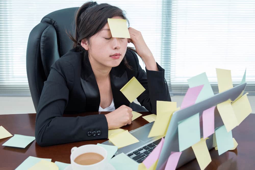 Stressreduktion am Arbeitsplatz junge Frau mit To-Do-Zetteln auf der Stirn