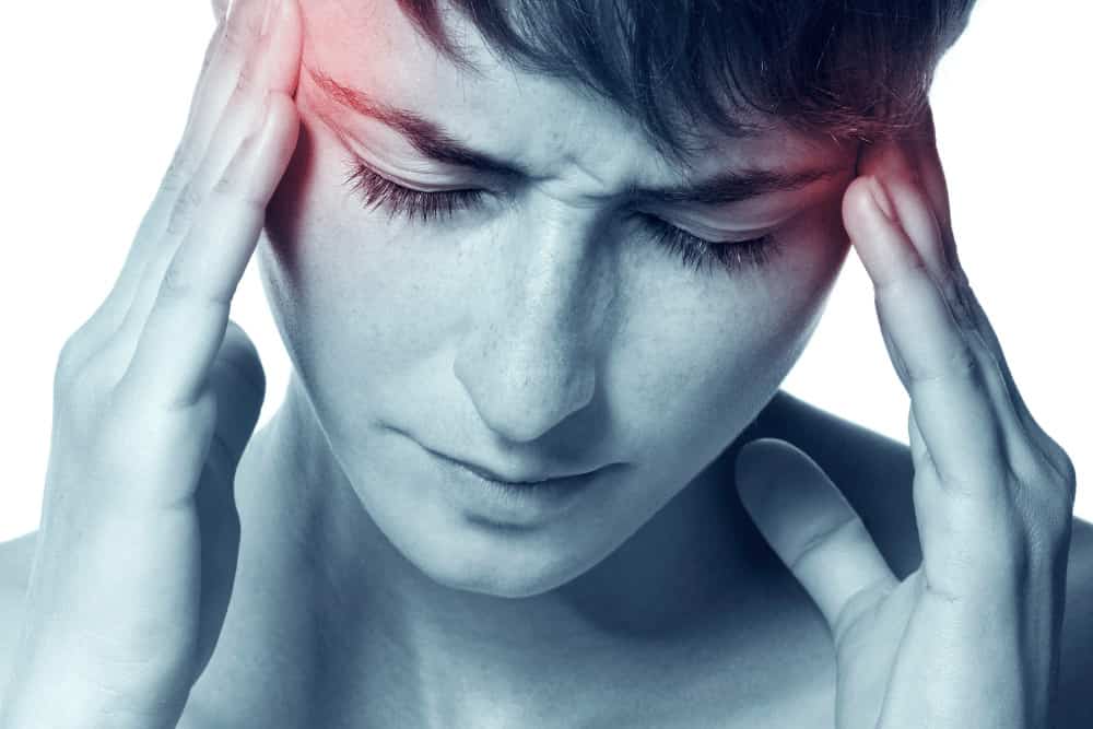Was hilft bei Migräne - junge Frau mit Schmerzen am Kopf