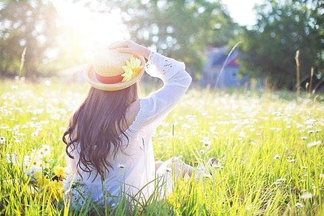 Junge Frau mit Sonnenhut auf lichtüberfluteter Blumenwiese