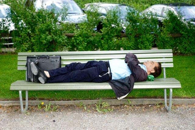 Wieviel Schlaf - Mann im Anzug schläft auf einer Parkbank