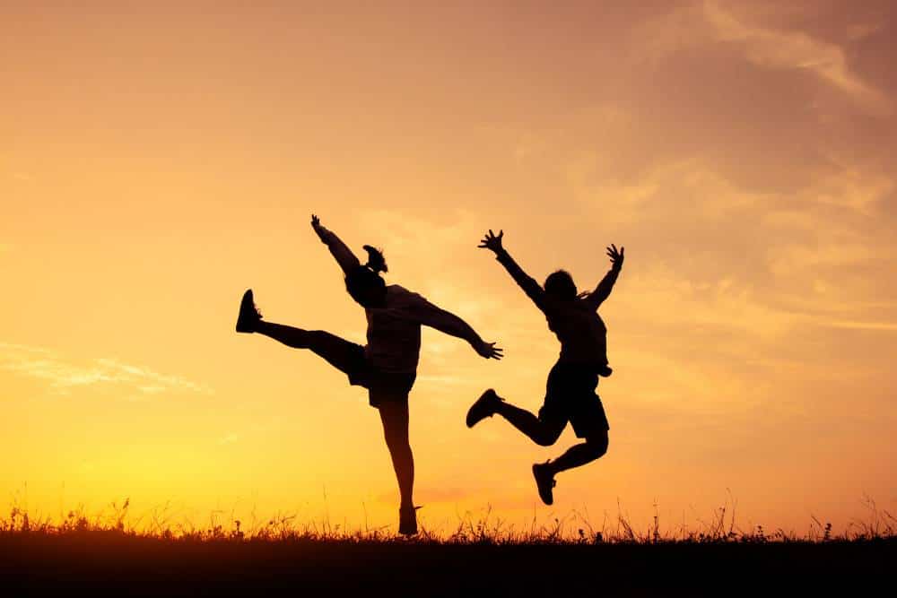 Zwei Menschen hüpfen über ein Feld