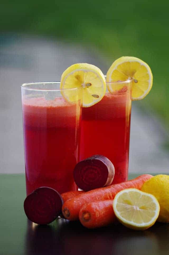 Zwei Gläser mit Rote-Beete-Saft und Zitronen-Deko, im Vordergrund rohes Gemüse