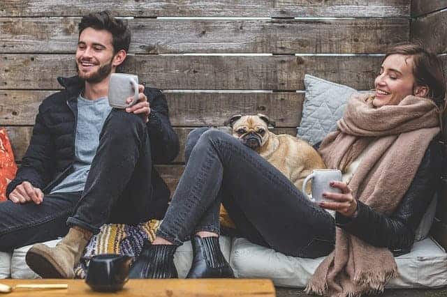 Zwei Freunde sitzen auf dem Sofa mit einer Tasse Kaffee und lachen